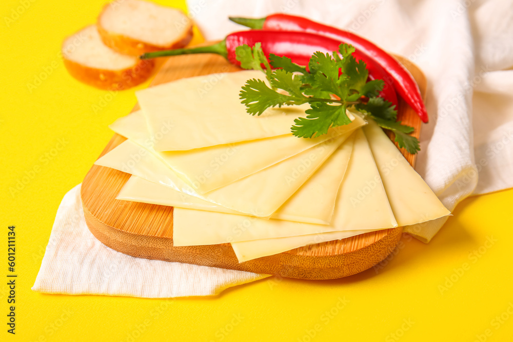 Board of tasty processed cheese with bread and chilli on yellow background