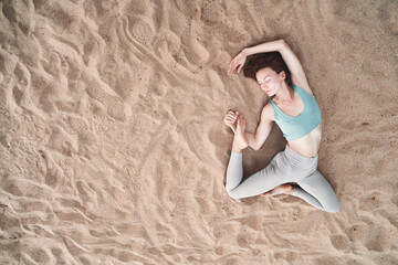 Wall Mural - Top view of woman practicing yoga on sand beach.