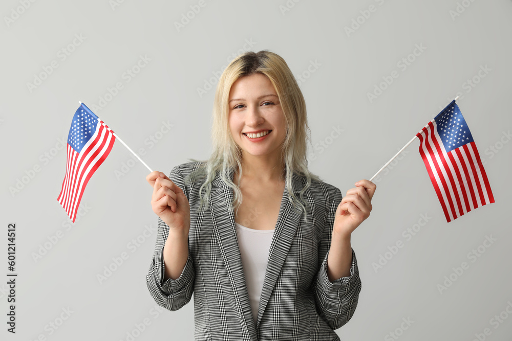 Young businesswoman with USA flags on grey background
