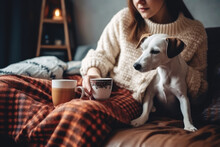 Cozy Woman In Knitted Winter Warm Sweater With Her Dog And Coffee During Resting On Couch At Home In Christmas Holidays.
