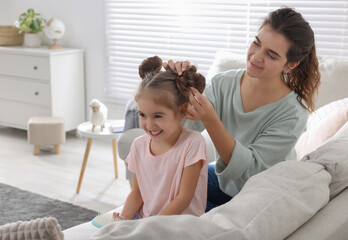 Wall Mural - Young mother and her daughter spending time together on sofa at home