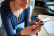 © Baba Images - Young woman using a smart phone at home