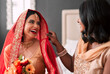 Happy, bride and bridesmaid getting ready for a wedding, laughing and helping in a room. Support, love and a young woman in traditional Indian clothes for marriage ceremony with a friend or sister