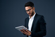 © Thaakirah/peopleimages.com - Technology, professional young businessman with tablet and in a studio background. Social networking or digital communication, isolated and male person with mobile device search on backdrop.