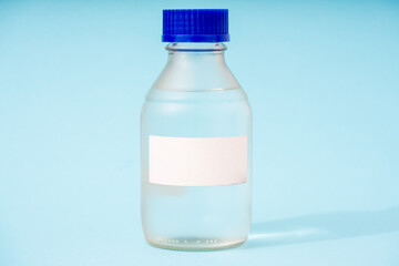 Canvas Print - transparent glass bottle for chemical or biological substances on a blue background