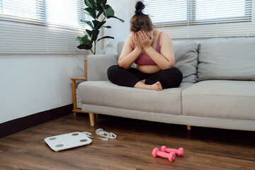 Obese Woman with fat upset bored of dieting Weight loss fail  Fat diet and scale sad asian woman on weight scale at home weight control.