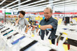 © caftor - Elderly male customer looking for a deal on smart watches in big electronics store