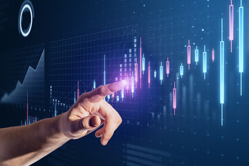 Aufkleber - Close up of male hand pointing at abstract glowing candlestick business chart on blue background. Trade, finance and market concept.