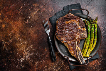 Wall Mural - BBQ Grilled Tomahawk or Cowboy with bone beef steak, roasted asparagus. Wooden background. Top view. Copy space