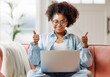 © JenkoAtaman - beautiful young smiling ethnic woman with curly hair uses laptop smiling, gesticulating and talking to online while sitting on sofa