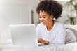 © JenkoAtaman - happy young african american woman relaxing with laptop at home lying in bed