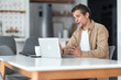 © Jelena - A middle-aged male freelancer having an online meeting with his colleagues on the laptop.