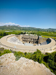 Wall Mural - Aerial view of the ancient theater of Aspendos, Turkey, on a sunny day. The mountains in the background provide a stunning backdrop.