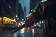 Gloved hand holding knife with city street at night in background. Crime concept.