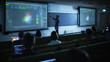 © Gorodenkoff - Young University Professor Explaining the Importance of Artificial Intelligence to a Group of Diverse Multiethnic Students in a Dark Auditorium. Teacher Showing Big Data Ecosystem on Two Big Screens