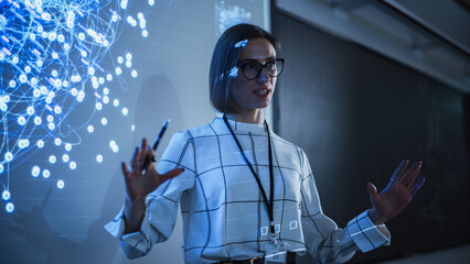 Young Businesswoman Giving a Data Science Presentation in a Dark Auditorium with Projecting Slideshow with Artificial Intelligence Neural Network Architecture. Business Startup and Education Concept