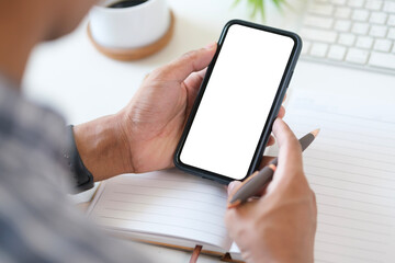 Wall Mural - close up view of man using smartphone at workstation. white empty screen ready for your app.
