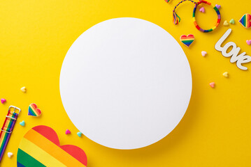 Wall Mural - A top-down view of LGBT pride parade accessories, featuring a rainbow colored postal, wristlet, pin badges, hearts, and more, on a vibrant yellow background with circle for text or an advertisement