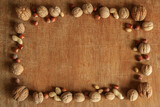 Fototapeta Desenie - A square frame of different kinds of nuts on an old wooden background.