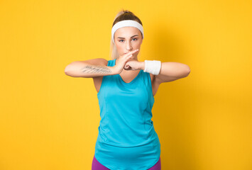 Fitness woman ready for physical exercising, isolated on yellow background. Half length of sportswoman shows her fists. Endurance athlete female person. 80s styling