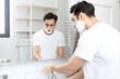 © Vitaliy - Handsome man looking at the mirror and shaving in the bathroom