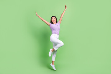 Wall Mural - Full body photo of funky attractive vietnamese woman jump dancing raised hands up crazy rhythm isolated on green color background