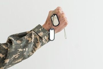 Wall Mural - Man in camouflage uniform holding military ID tags over wooden background.