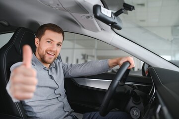 Wall Mural - Happy young driver behind the wheel inside new car. Lifestyle scene in the car dealership