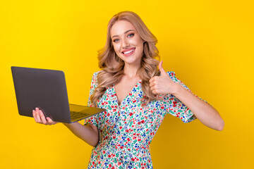 Wall Mural - Portrait of positive cute lady wear trendy clothes hold netbook thumb up quality modern technology isolated on yellow color background