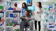 © DC Studio - Client with disability and social worker receiving medical supplies in pharmacy, buying healthcare products. Customer in wheelchair receiving pharmaceutical drugs, pharmacist giving advice.