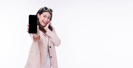 Cheerful excited asian woman sunglasses showing mobile phone empty screen standing on isolated white background. Businesswomen wear suit holding smartphone looking camera. Technology app on cellphone