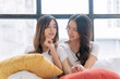 © kaew6566 - Cheerful lesbian asian woman sitting together relax with pillows on white bed at home. Romantic couple young girl embracing together looking each other with love at home. Lifestyle lgbt relationship.
