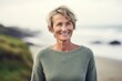 © Hanne Bauer - Portrait of smiling senior woman standing on the beach at the coast