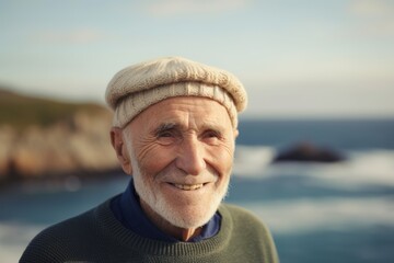 Wall Mural - Portrait of happy senior man in cap and sweater standing at beach