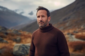 Wall Mural - Portrait of a handsome man in a brown sweater against the background of mountains