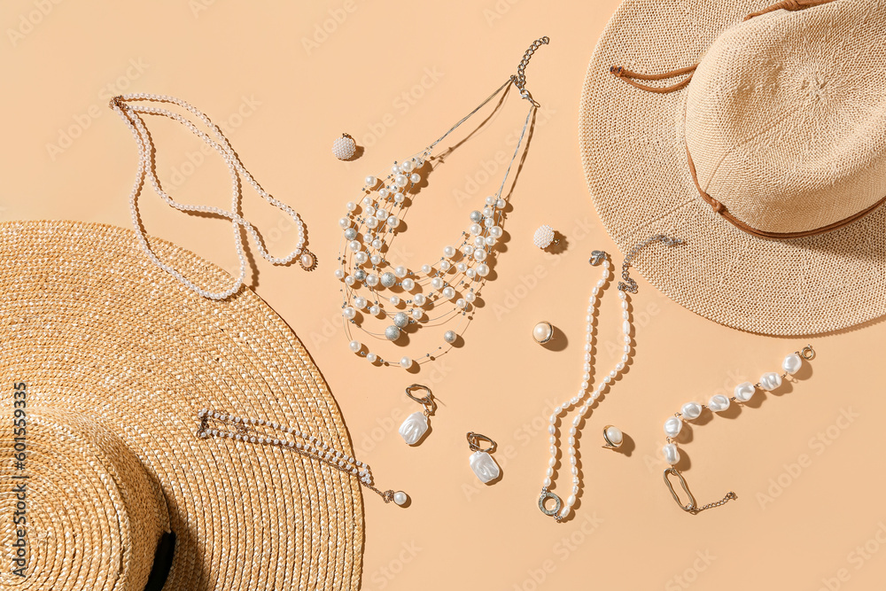 Summer hats with stylish jewelry on beige background