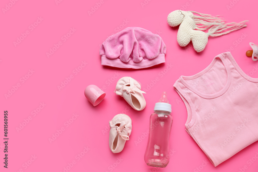 Composition with baby clothes, toy and bottle on pink background