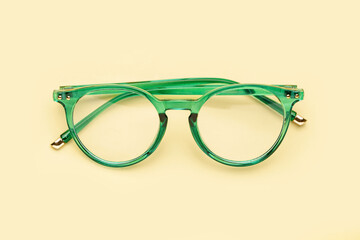 Wall Mural - Stylish green eyeglasses on pale yellow background