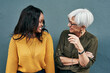 © A. Frank/peopleimages.com - Senior businesswoman, break and conversation with employee, friend or colleague in discussion outside work on blue background. Women, talking and happy together or black woman, mature person smile