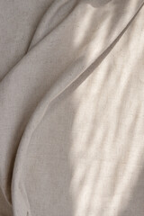 Draped beige linen fabric texture background with natural sunlight shadows, neutral lifestyle bohemian backdrop
