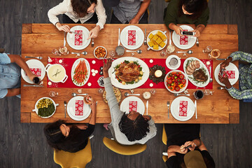 Wall Mural - Thanksgiving, overhead and friends sitting around a table for a food meal during a celebration event. Family, roast or nutrition with a man and woman group in the living room for a social gathering