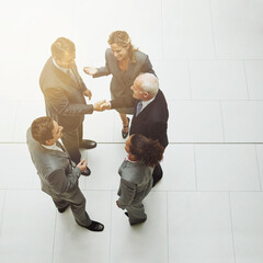 Wall Mural - Top view, handshake and group of business people in meeting for deal, agreement or crm on mockup. Above, shaking hands and employees with b2b collaboration, partnership and welcome to company office.