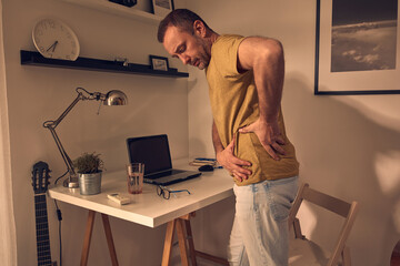 Wall Mural - Man with hip, back, spine, hernia and sciatica pain at home.