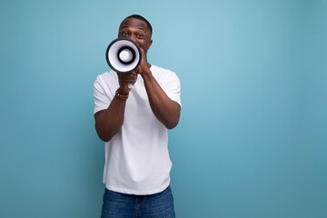 Wall Mural - casual 30s african man with short hair in white t-shirt speaks into loudspeaker interesting news