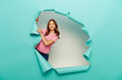 © LIGHTFIELD STUDIOS - Cheerful preteen girl in casual clothes having fun while celebrating child protection day and standing behind hole in blue paper on white background