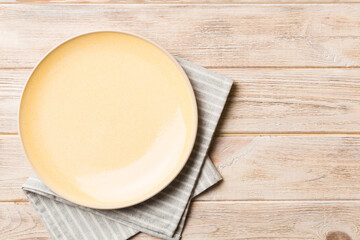 Top view on colored background empty round yellow plate on tablecloth for food. Empty dish on napkin with space for your design