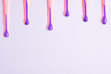 Wall Mural - Pink and purple liquid drops of paint color flow down on white paper. Abstract art. Colorful paint dripping on the white with copy space..