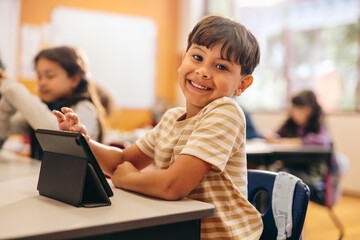 Child development in action as young kid learns to code with a tablet in school