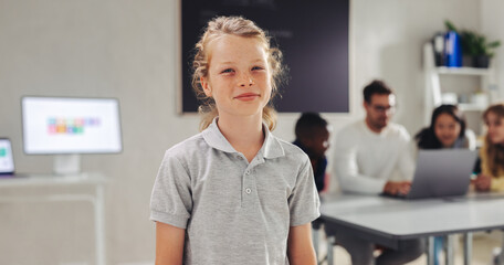 Wall Mural - Male student looking at the camera in a digital literacy classroom, with his teacher and classmates coding in the background