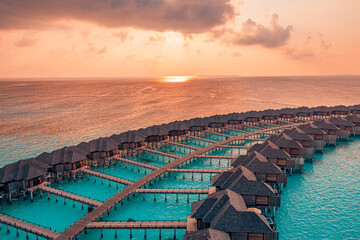 Wall Mural - Amazing sunset panorama at Maldives. Luxury resort water villas bungalows seascape with colorful sky. Best travel landscape sea bay lagoon romantic colors. Aerial seascape beach dream vacation concept